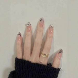 French almond press-on nails with cat eye nude base, black dots, bows, and lace designs