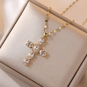 Detail of a gold cross pendant necklace with clear oval cubic zirconia in a jewelry box