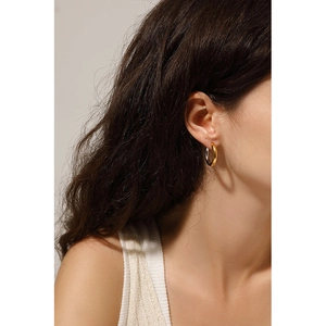 Detail of two-tone gold and silver chunky hoop earrings worn on a model with warm lighting