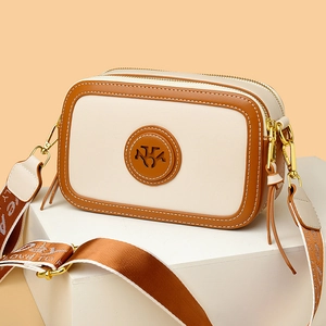 Retro two-tone leather camera bag with wide woven strap and circular cutout logo