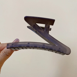 Detail of a geometric dark purple acrylic hair claw clip with nonslip teeth