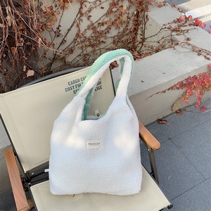 Close-up of fluffy sherpa tote bag in white and mint green on an outdoor chair