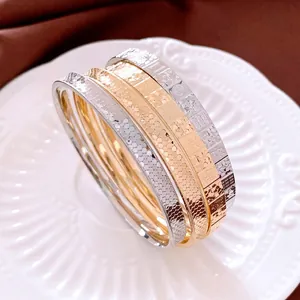Three-piece metal bangle set with gold, silver, and rose gold embossed honeycomb textures