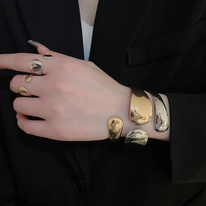 Detail of high-polish gold and silver oval open bangles and rings on a model