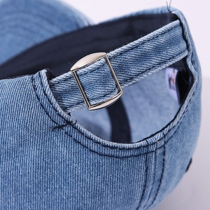 Detailed macro view of the adjustable metal buckle and washed denim texture on a baseball cap