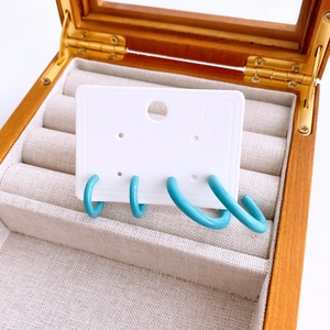 Macro view of sky blue geometric hollow round earrings set in a wooden jewelry box