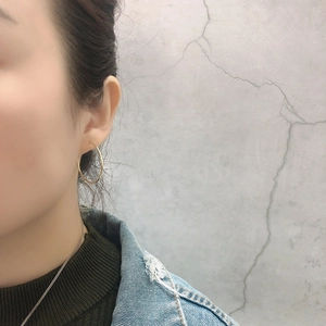 Minimalist large golden hoop earrings with a polished finish worn on a fashion model