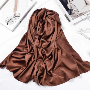 Flat lay of brown silk scarf with elegant folds, glasses, and fashion magazine setup