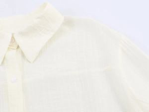 Detail view of cream textured fabric shirt with classic collar and white buttons