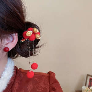 Detail of New Chinese style hair clip with red pom-poms, gold ingots and tassels on hair