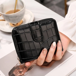 Detail of black crocodile texture wallet with metal zipper and snap button closure