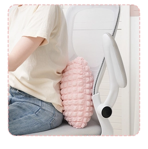 Close-up of pink leaf-shaped lumbar pillow with textured grid fabric on a white office chair
