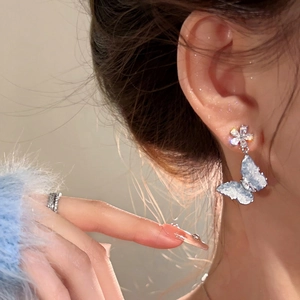 Detailed close-up showing elegant blue butterfly earrings with a sparkling flower stud.