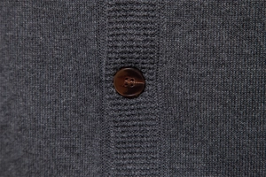 Detailed close-up of dark brown resin button on grey knitted cardigan for men