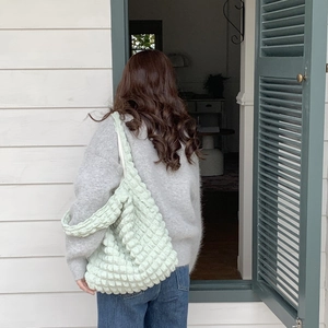 Detail of mint green puffy shoulder bag showing cloud-like texture and large capacity