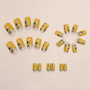Yellow corn theme press-on nails with golden glitter heart accents in a 24-piece set