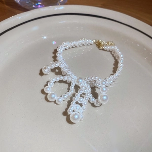 Vue détaillée d'un collier de perles en forme de nœud avec fermoir doré sur un plateau