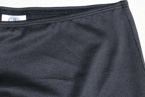 Close-up of black tight-fit mini skirt waist seam and size S tag on knit fabric
