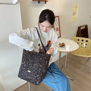 Detail of leopard print canvas tote bag with metal logo in a retro cafe setting