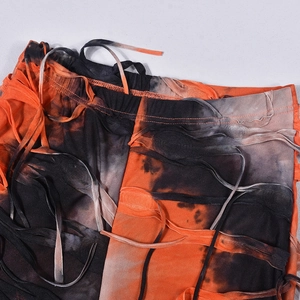 Dettaglio dei pantaloni a zampa con tessuto in maglia tie-dye e elementi con nappe