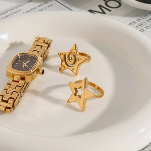 Montre vintage dorée et bagues étoile présentées sur une assiette blanche