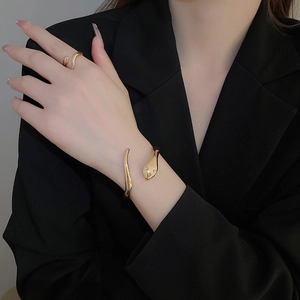 Detail of elegant gold snake-shaped open bracelet and ring set worn on model