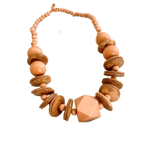 Ethnic style necklace with brown wooden beads and coconut shell pendants on white background