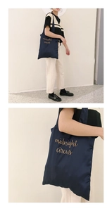 Detail of navy blue satin tote bag with gold midnight circus embroidery