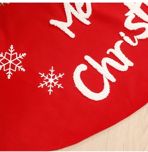 Detail of red Christmas tree skirt with white snowflake embroidery and Merry Christmas text