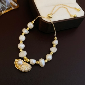 Macro view of freshwater pearl bracelet with golden shell charm and adjustable bolo chain