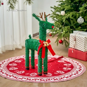 Green Christmas reindeer figurine with red bow and gold bell on a snowflake tree skirt