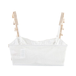 Detail of white crop top featuring shell tassel straps and elastic smocked back