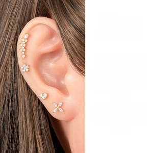 Detailed view of zircon-studded gold flat back lip rings and tragus jewelry on a model