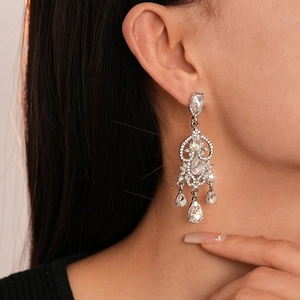 Close-up of sparkling silver chandelier earrings with teardrop diamonds on model