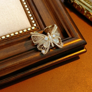 Macro shot of vintage gold bow ring featuring woven wire textures and zircon stones