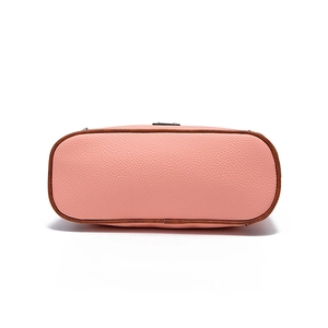 Detail view of pink lychee leather crossbody bag bottom with brown painted edges