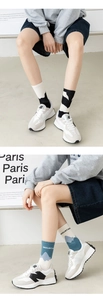 Detail view of stylish knitted mid-calf socks with mountain patterns and retro sneakers