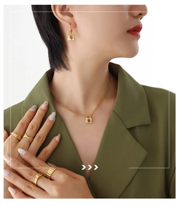 Detailed view of gold chain necklace and earrings with purple zircon stone lock charms