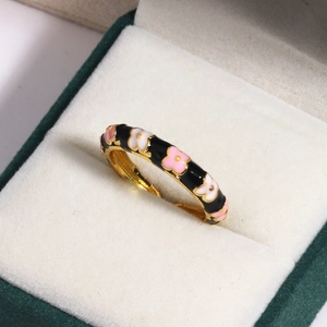 Macro shot of gold floral ring with colorful enamel inlay on velvet jewelry box insert