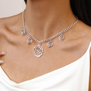 Detail of silver clavicle necklace featuring five artistic spiral metal charms on a model