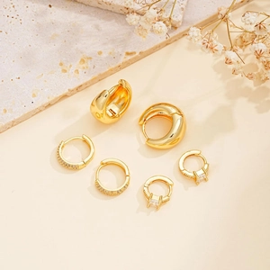 Three-piece gold earring set with geometric cubic zirconia accents on marble stone