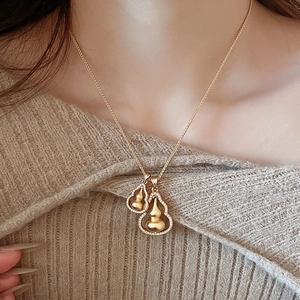 Dettaglio della collana a doppia zucca dorata con zirconi lucenti su maglione lavorato