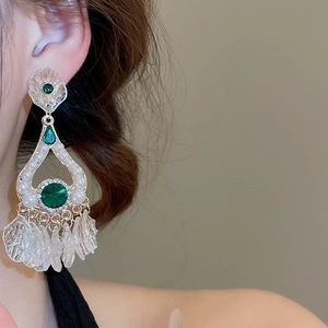 Close-up of vintage emerald waterdrop earrings with pearls and crystal leaf tassels on model