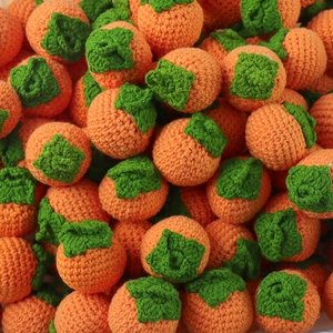 Handmade knitted orange persimmons craft keychains with green stems in bulk pile
