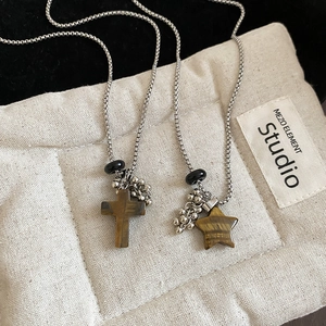 Detail of vintage beaded necklace featuring stone cross and star pendants on silver chain