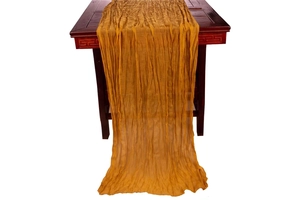 Detail of mustard yellow cheesecloth table runner showing wrinkled texture and drape