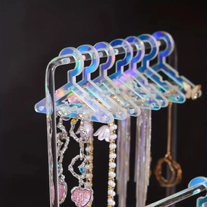 Close-up of holographic acrylic earring rack with mini clothes hanger design hooks