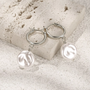 Close-up of elegant S925 silver pearl drop earrings on a natural stone base
