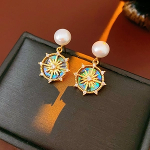 Macro view of gold plated mother-of-pearl stud earrings with sunburst star detail