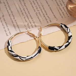 Vintage style gold hoop earrings with black and white striped leather wrap on beige paper
